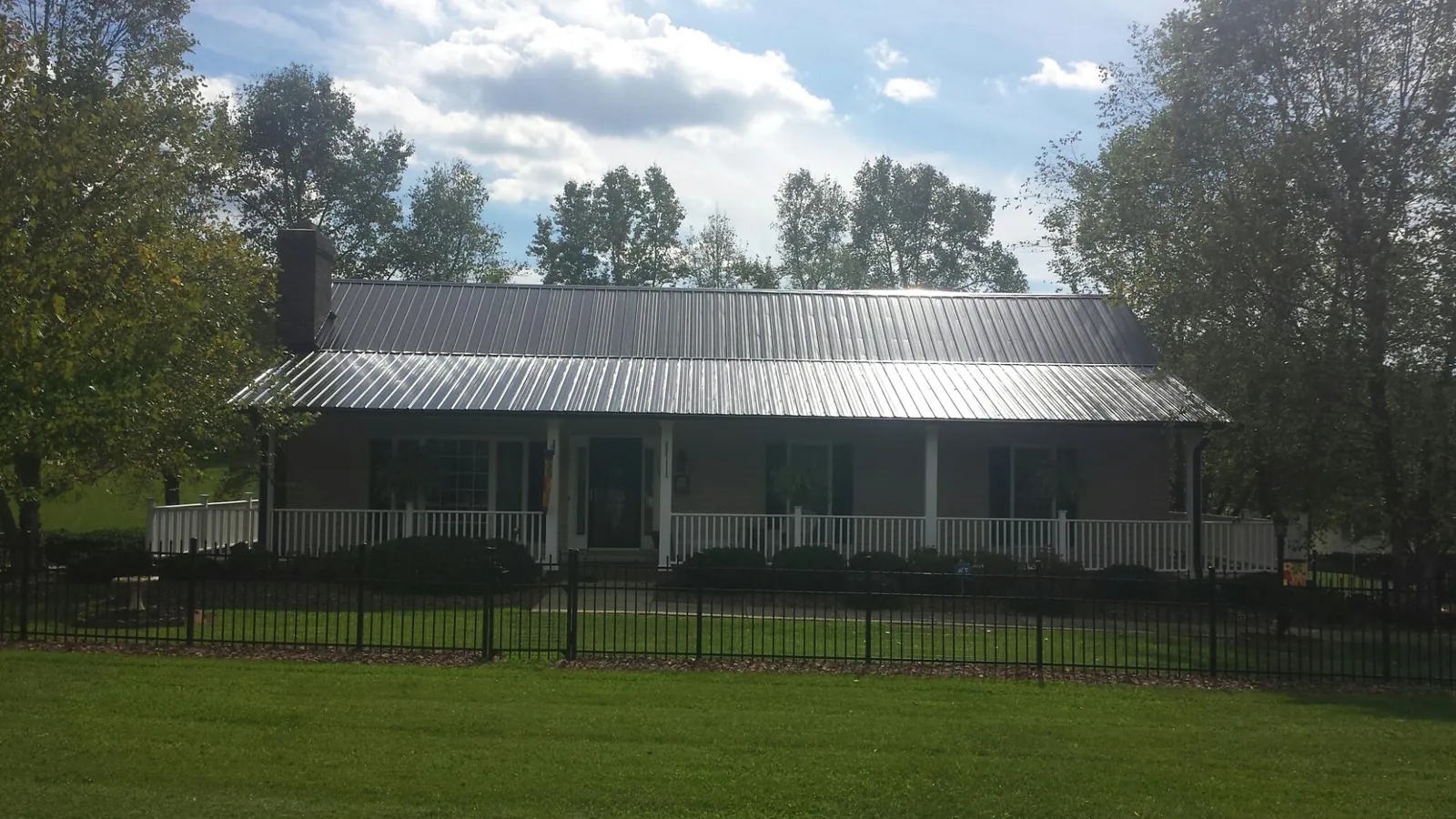 Gray metal roof on a brick ranch with a full width front porch — Gutter Guard Installation work by our crew in Wells